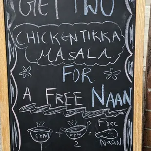 a blackboard with a sign that says get two chicken tikka masala for a free nan