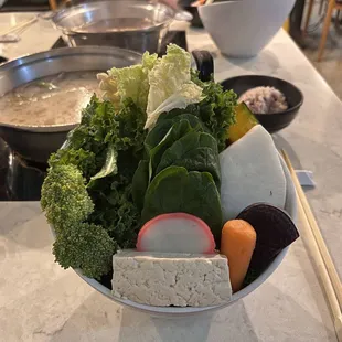Massive bowl of vegetables, fish cake, tofu, and noodles at the bottom