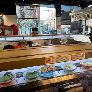 a sushi counter with a variety of bowls of food