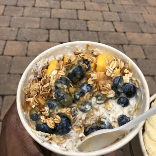 Overnight Oats with Yogurt, topped with Granola, Peanut Butter Sauce, Mangos, and Blueberries