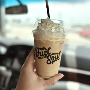 a hand holding a cup of iced coffee