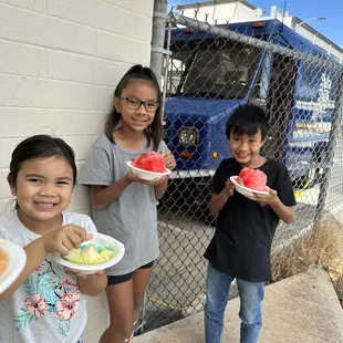 three children holding plates of watermelon