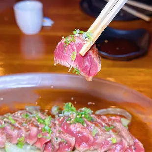 a person holding chopsticks over a plate of sushi