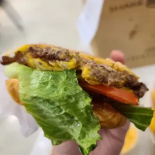 a hand holding a hamburger with lettuce and tomato