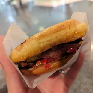 a person holding a sandwich in their hand