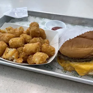 a hamburger and tater tots on a tray