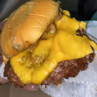 a hand holding a cheeseburger