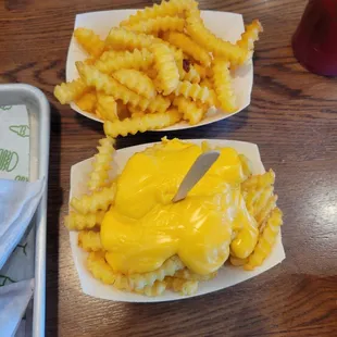 a plate of cheese fries and a tray of cheese fries
