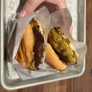 a hand holding a cheeseburger and a cheeseburger