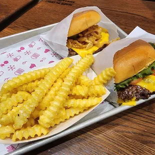 two burgers and french fries on a tray
