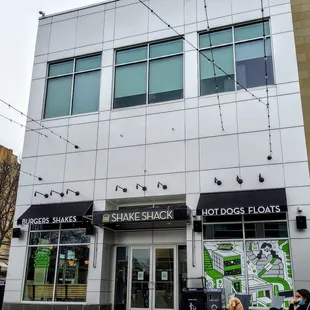 two people walking in front of shake shack