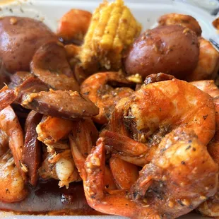a plate of shrimp, potatoes and corn