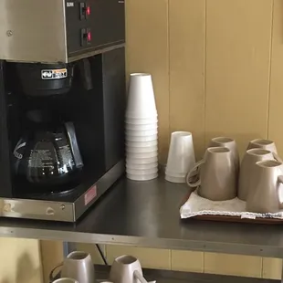 a coffee maker and cups on a shelf