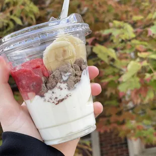 a hand holding a cup of yogurt