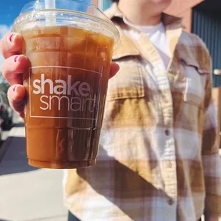 a woman holding a cup of iced coffee