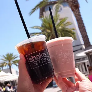 a hand holding two drinks