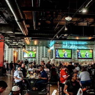 a large group of people sitting at tables in a sports bar