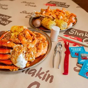 two plates of crab legs and corn on the cob