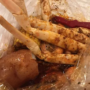 Big potato and corn on the cob with crab legs and shrimp.