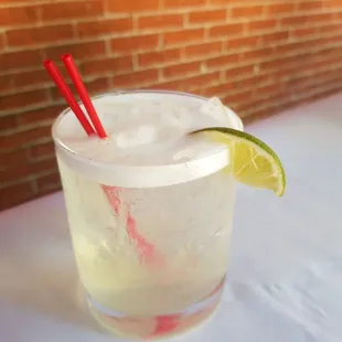 a close up of a drink with a red straw and a lime slice