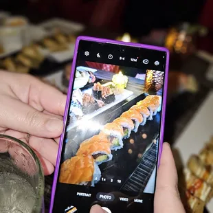 a person taking a picture of sushi