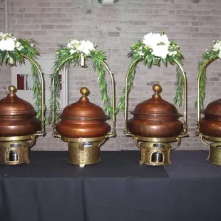 a row of copper urns with flowers in them