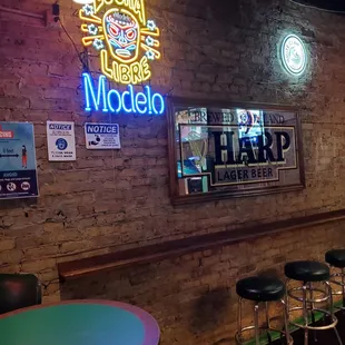 neon signs on brick wall and bar stools