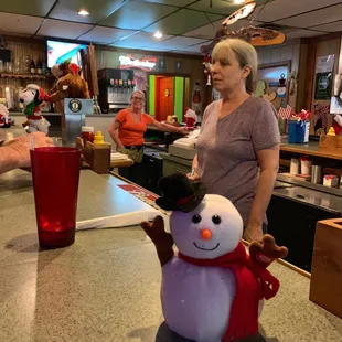a woman standing at a counter with a snowman
