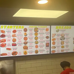 a man standing in front of a menu board