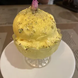 a yellow ice cream with a pink flower on top