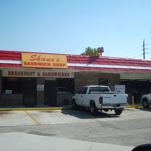 a white truck parked in front of a sandwich shop