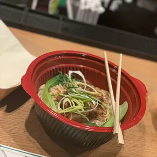 a bowl of noodles and chopsticks