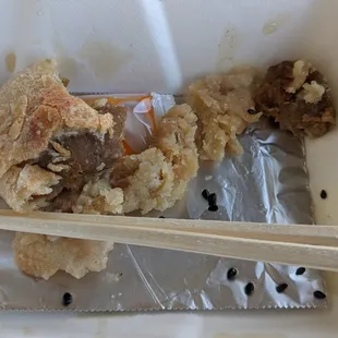a piece of food in a container with chopsticks