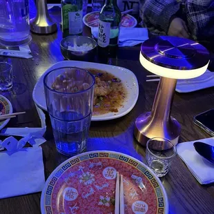 a group of people sitting at a table with plates of food and chopsticks