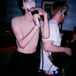 a man with white paint on his face singing into a microphone
