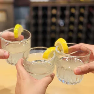 two people toasting with lemon wedges