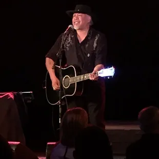 a man playing a guitar and singing into a microphone