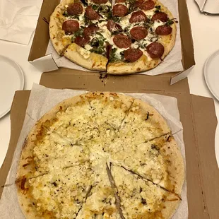 two pizzas in boxes on a table