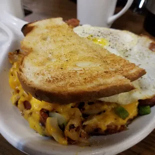 Breakfast Skillet with home fries, onion, green peppers and cheese. Topped with a couple over easy eggs and sour dough toast