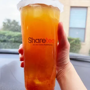 a person holding a cup of orange juice