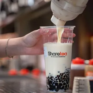 a person pouring milk into a cup