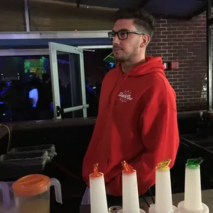 a man in a red hoodie standing in front of a bar