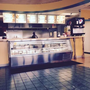 Interior: Counter to order at, case displaying side dishes, kitchen behind counter.