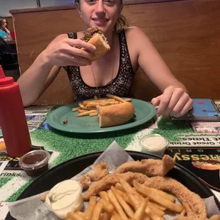 a woman eating a sandwich and fries