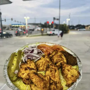 a hand holding a foil container of food