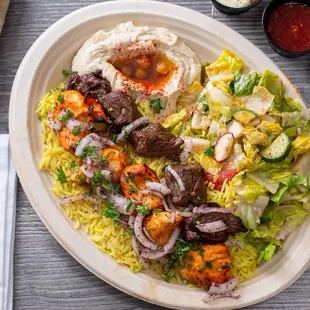 Mixed Grill Plate- Beef and Chicken kabob over rice, salad, hummus, and fresh baked bread. including our tahini, garlic, and chili sauce.