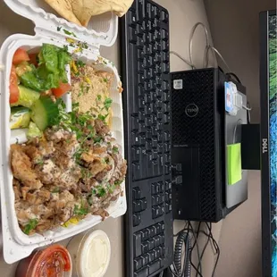 a laptop, keyboard, and tray of food