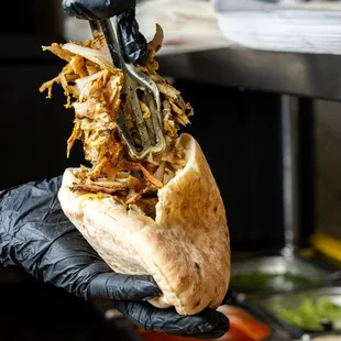 a hand holding a pita sandwich