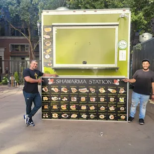 two men standing in front of a food truck
