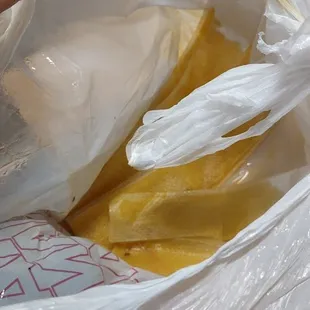 a person holding a sandwich wrapped in plastic